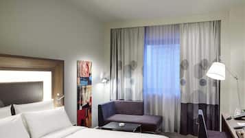 Ein Hotelzimmer mit einem Bett, einem Schreibtisch mit Stuhl, einer Couch, einer Lampe und einem Bild an der Wand.