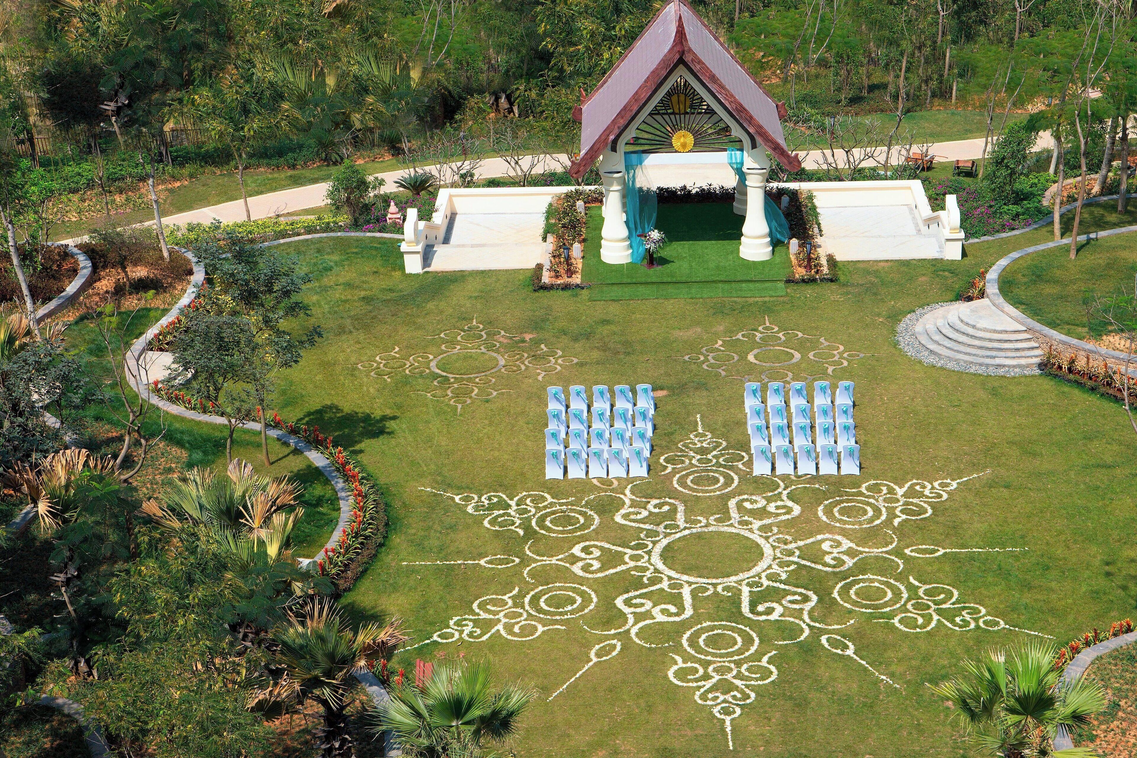 A landscaped garden with a gazebo, a patterned lawn, and rows of chairs.