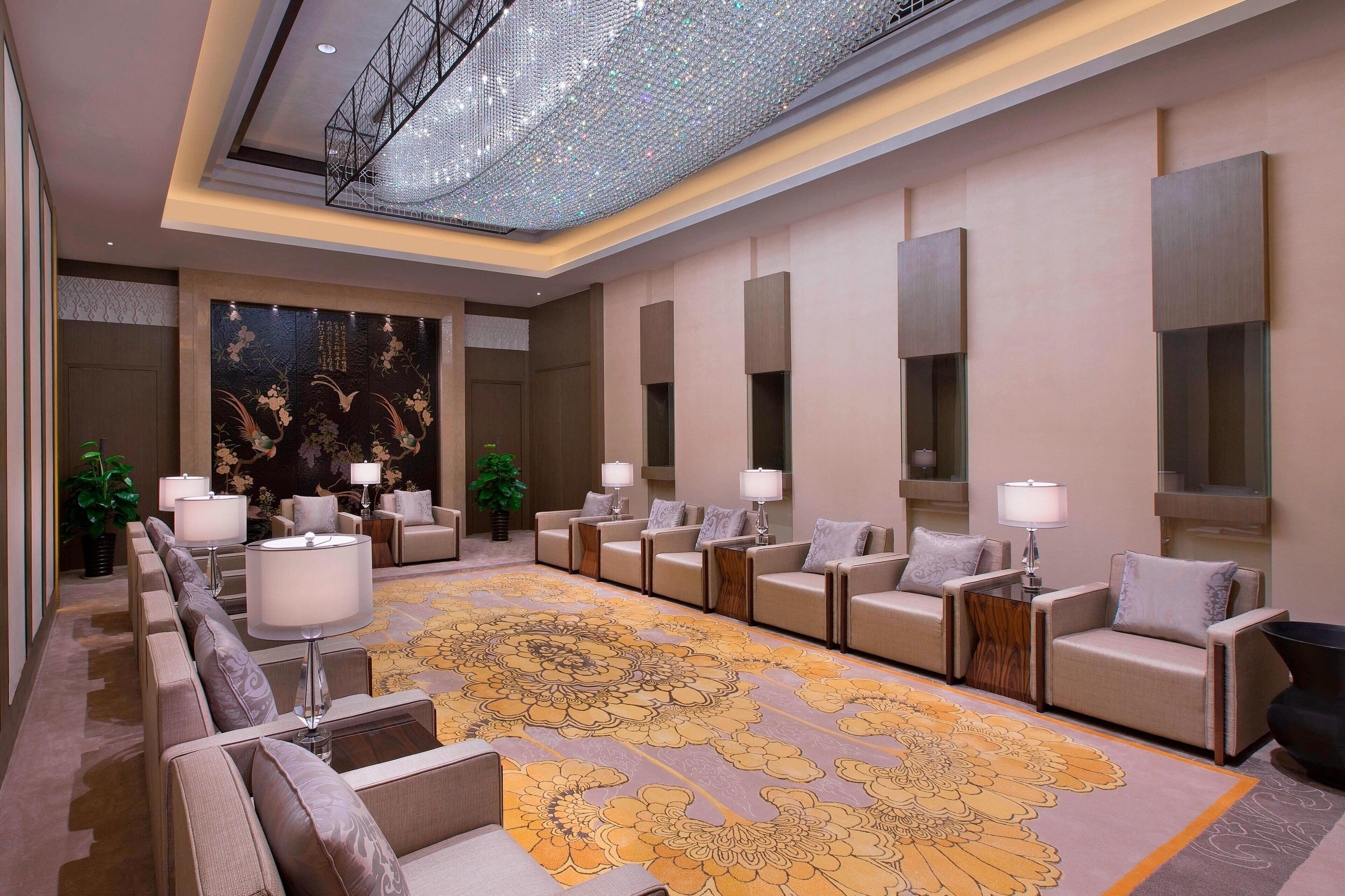 A spacious lobby with a patterned carpet, multiple seating areas, and a decorative wall.