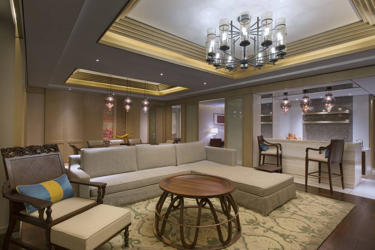 A modern living room with a sectional sofa, a round coffee table, and a dining area with chairs.