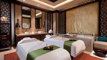 Relax in a serene spa room with two massage beds, a modern sink, and a beautifully carved wall feature.