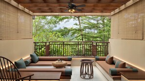 A modern outdoor seating area with a ceiling fan, wooden furniture, and a view of lush greenery. - Sheraton Grand Xishuangbanna Hotel (Xishuangbanna Dai)