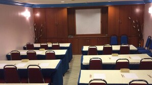 A conference room with rows of tables and chairs, a projector screen, and wooden cabinets. - Hotel DeLeeton (Kota Kinabalu)