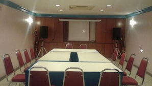 A conference room with a long table, red chairs, a projector screen, and speakers. - Hotel DeLeeton (Kota Kinabalu)