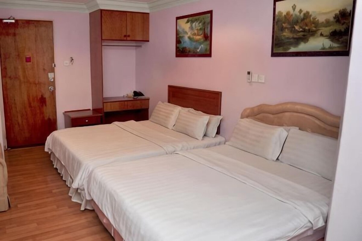 Una habitación con dos camas, un armario de madera, un escritorio y un cuadro en la pared.