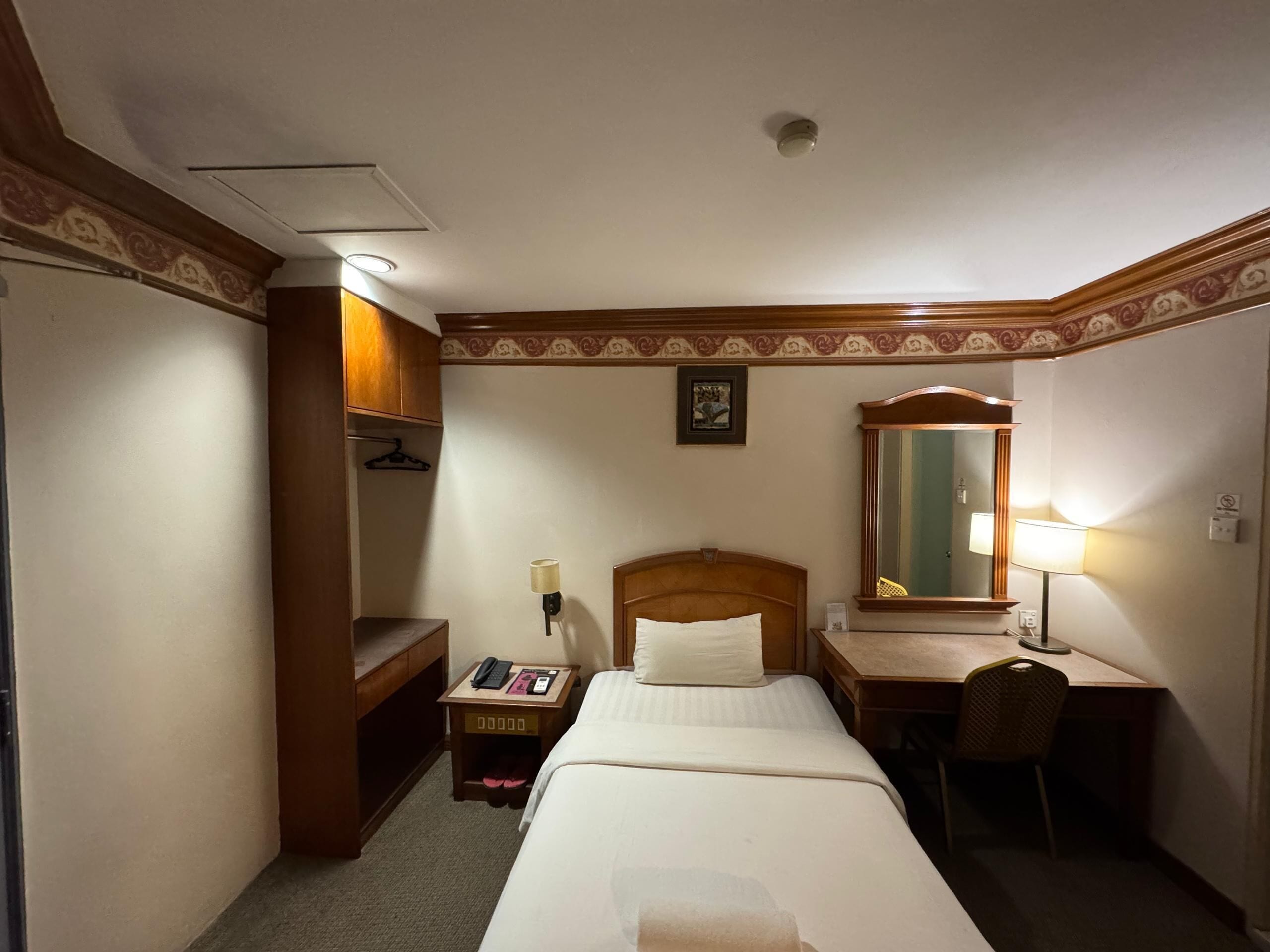 Una habitación de hotel con cama, escritorio, silla y espejo.