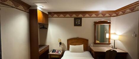 Una habitación de hotel con cama, escritorio, silla y espejo.