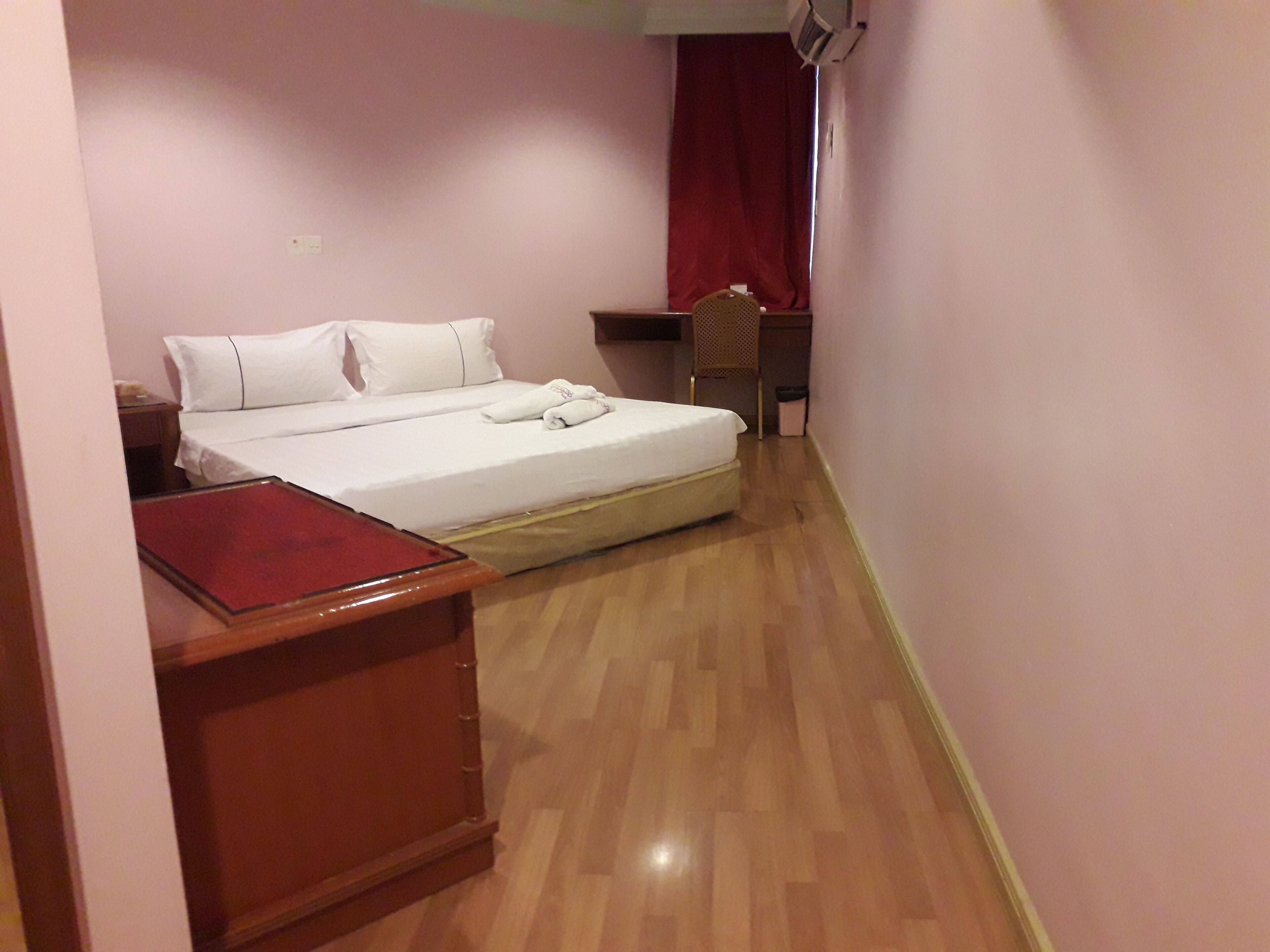 Un dormitorio pequeño y ordenado con una cama individual, una mesita de noche de madera, un escritorio y una silla.