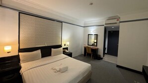 A hotel room with a large bed, a desk with a chair, a mirror, and a small table with a lamp. - Hotel DeLeeton (Kota Kinabalu)