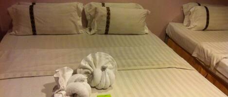 Une chambre d’hôtel avec deux lits, chacun étant équipé de draps et d’oreillers blancs. Des serviettes pliées sont posées sur les lits.