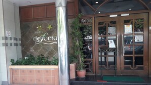 A hotel entrance with a 'No Smoking' sign, a 'Hotel deFeet' sign, and a 'Please make deliveries to side door' sign. - Hotel DeLeeton (Kota Kinabalu)