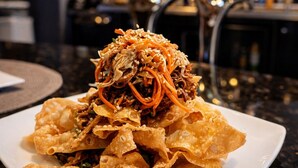 Une assiette remplie de frites croustillantes et dorées, recouverte de viande et de légumes émincés.