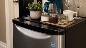 Une petite cuisine équipée d’une machine à café, d’une plante en pot et d’un plateau avec des bocaux et des verres.