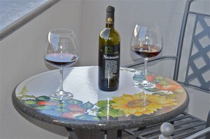 A round table with a floral design, a bottle of wine, and two glasses of red wine.