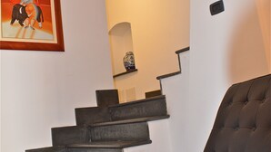 A modern staircase with dark steps leading to a landing, a black leather chair, and a framed artwork on the wall. - B&B Porta delle Madonie (Campofelice di Roccella)