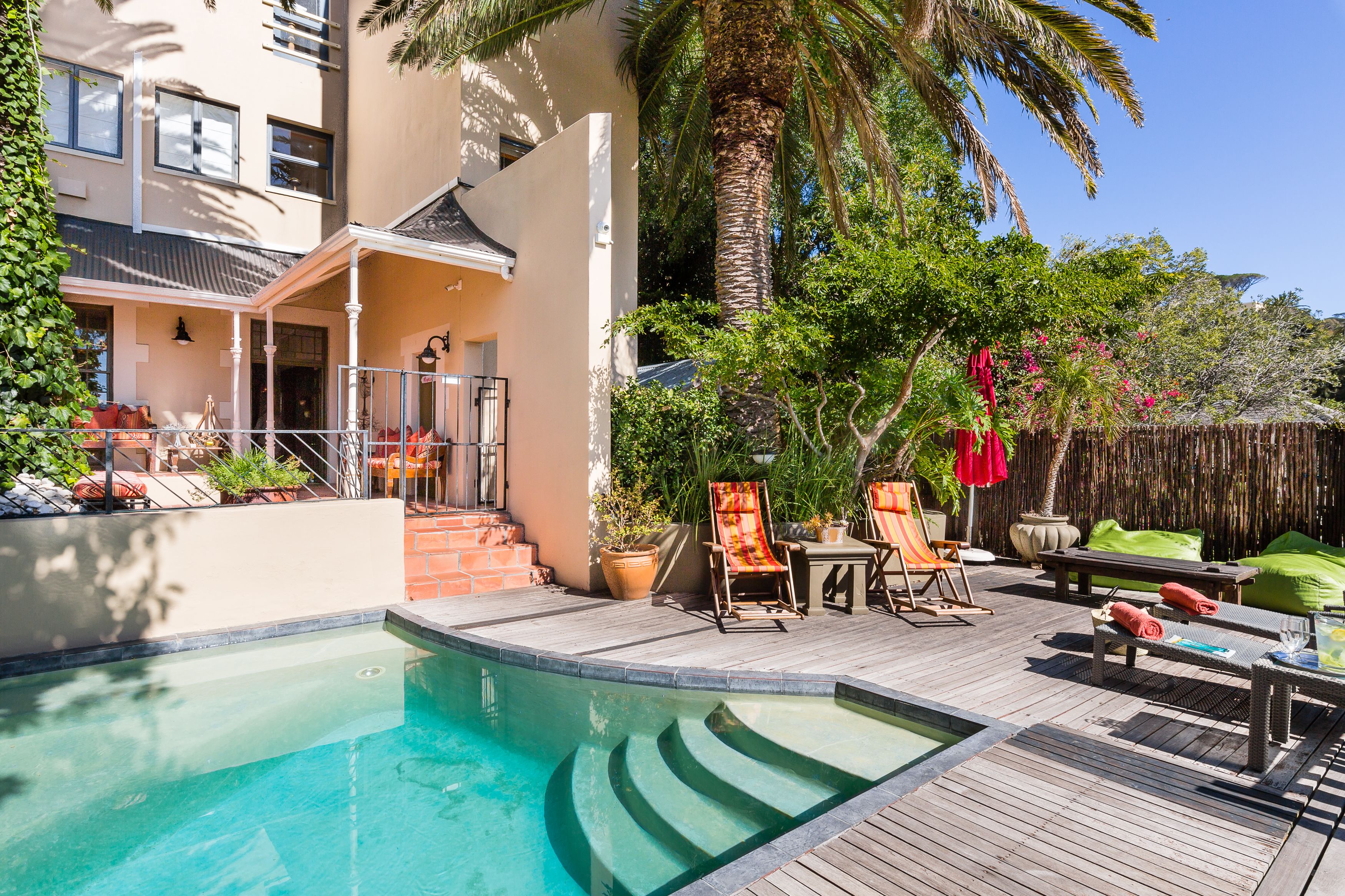 A pool area with a wooden deck, lounge chairs, and a small table.