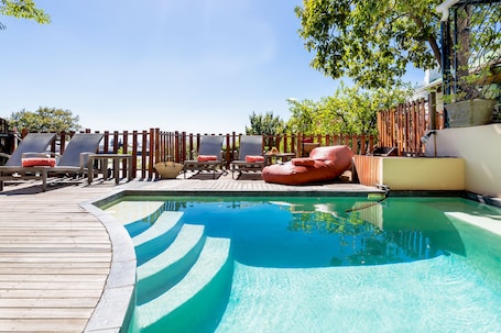 Una piscina al aire libre, sombrillas, sillones reclinables de piscina