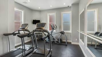Un gimnasio con cintas de correr, bicicletas estáticas y mancuernas.
