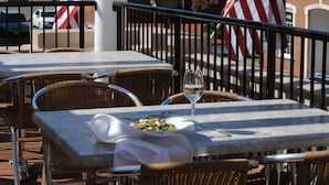 Outdoor dining tables with wicker chairs, a glass of wine, and an American flag. - The Gin Hotel, an Ascend Collection Hotel (Lexington)