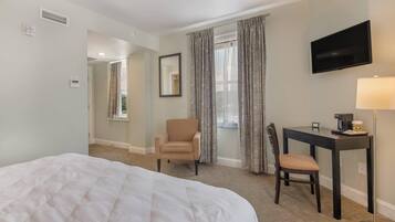 Une chambre d’hôtel avec un grand lit, un bureau avec une chaise, une télévision et une lampe.