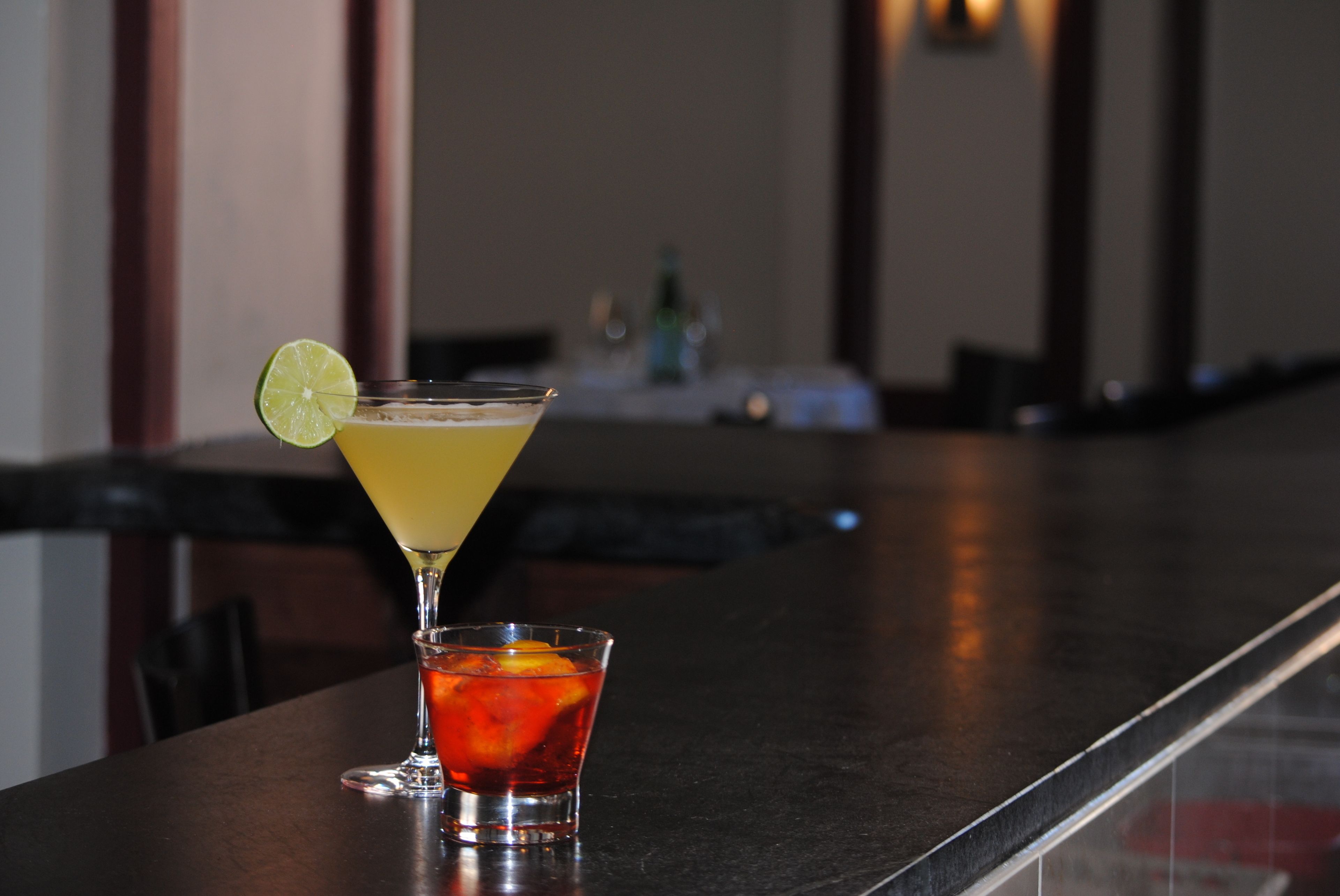 Un bar avec un verre à martini et un petit verre à liqueur posés sur le comptoir.
