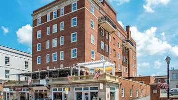 Experience the classic charm of the Robert E. Lee Hotel, featuring a historic red brick facade and a balcony with American flags.