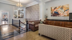 A lobby with a brown leather sofa, patterned armchair, and a large abstract painting on the wall. - The Gin Hotel, an Ascend Collection Hotel (Lexington)
