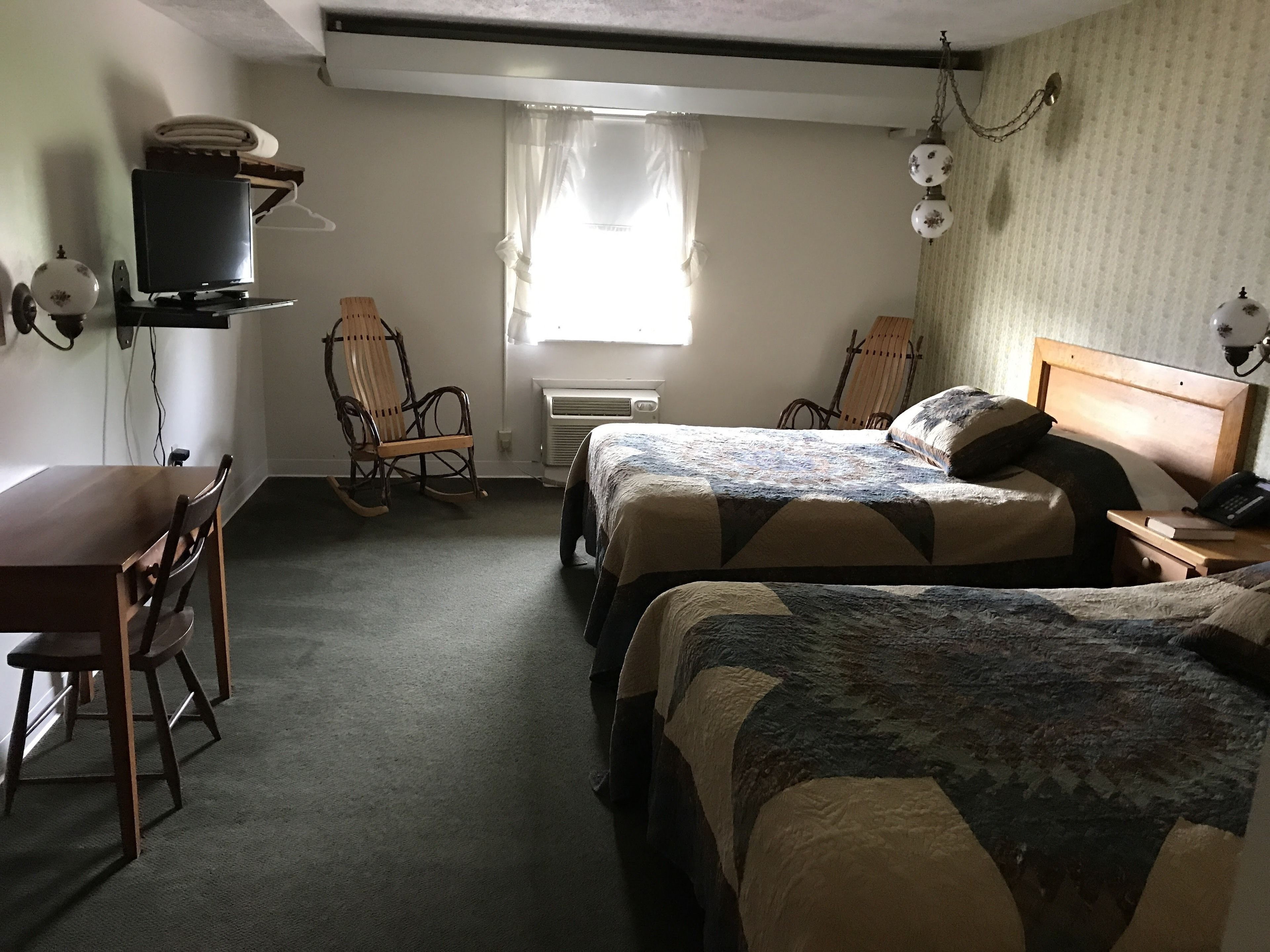 Een kamer met twee bedden, een bureau, een stoel en een raam met gordijnen.