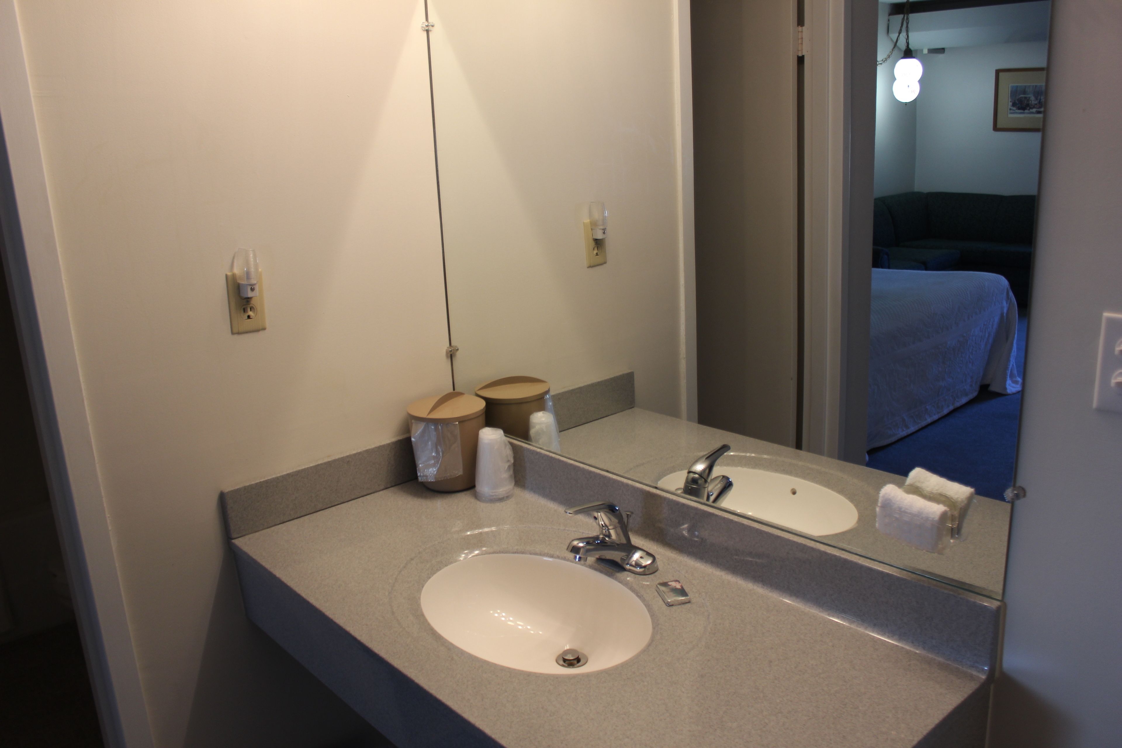 A hotel bathroom with a sink, mirror, and toiletries.