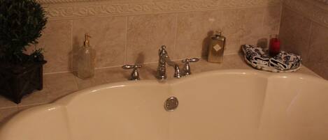Un baño con un espejo grande y decorativo, una bañera y un lavamanos.