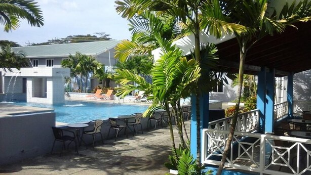 A pool area with lounge chairs and a covered seating area. - Green Palm Boutique Hotel (Crown Point)