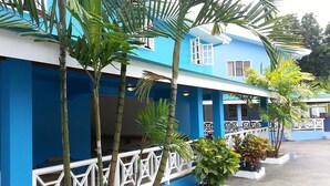 A blue building with white railings and potted plants. - Green Palm Boutique Hotel (Crown Point)