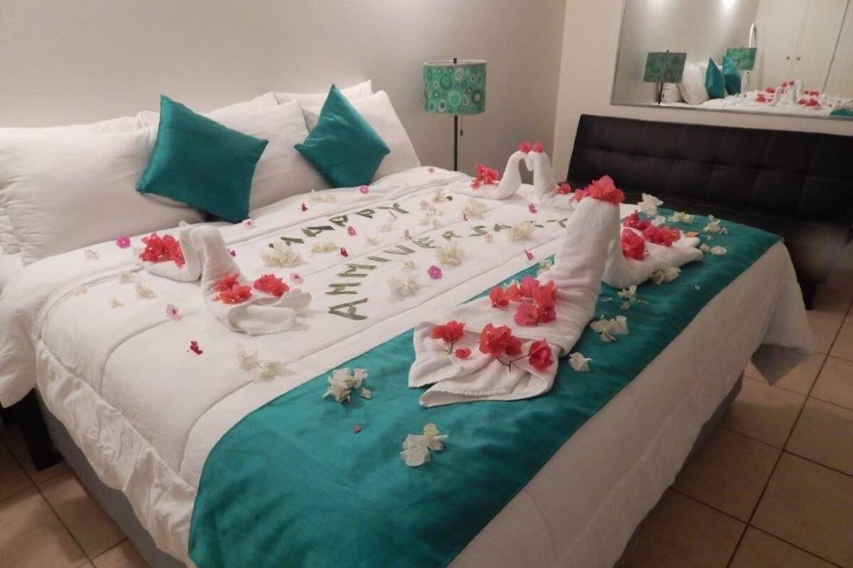 A neatly made bed with a teal bedspread, white pillows, and a floral arrangement on the bed.