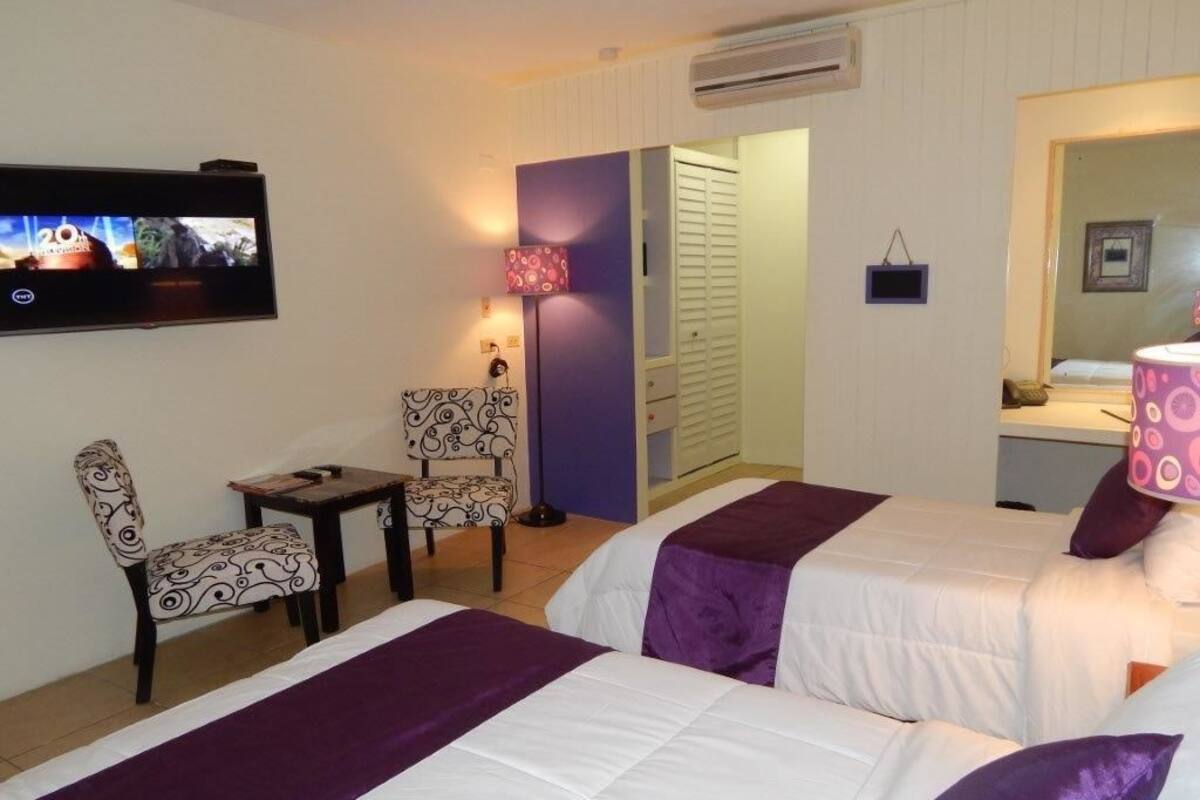A hotel room with two beds, a TV, a desk, and a chair.