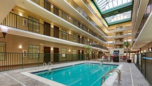Una piscina cubierta de varios niveles con techo de vidrio, múltiples balcones y una zona de recepción.