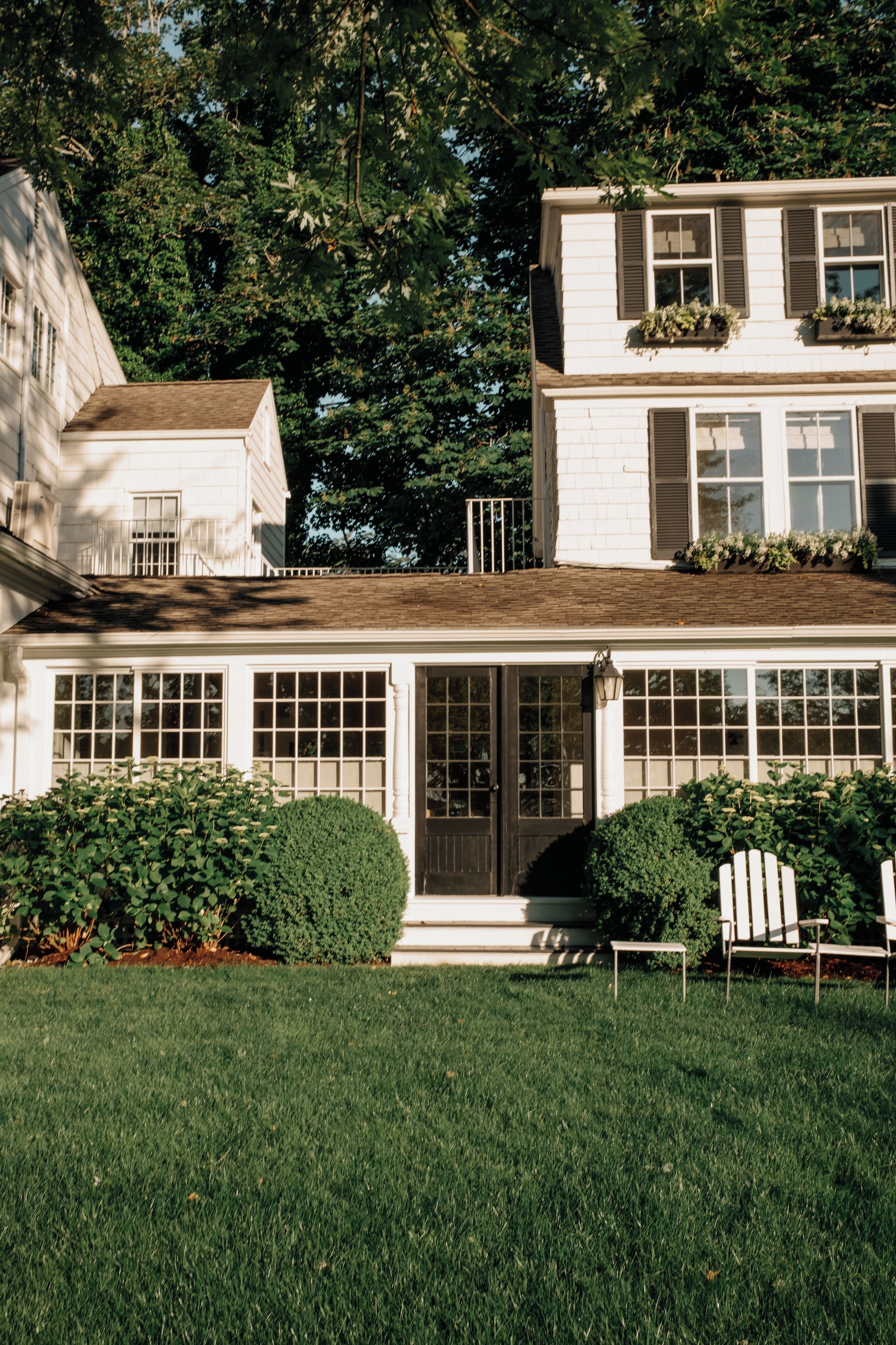 A two-story house with a front porch, large windows, and a well-maintained lawn.