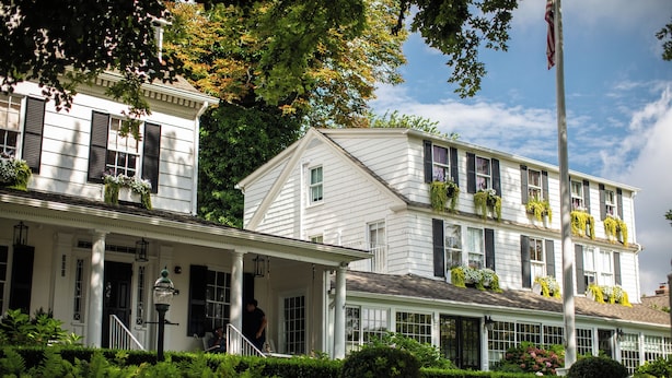 A two-story building with a porch and a flagpole. - The Maidstone (East Hampton)
