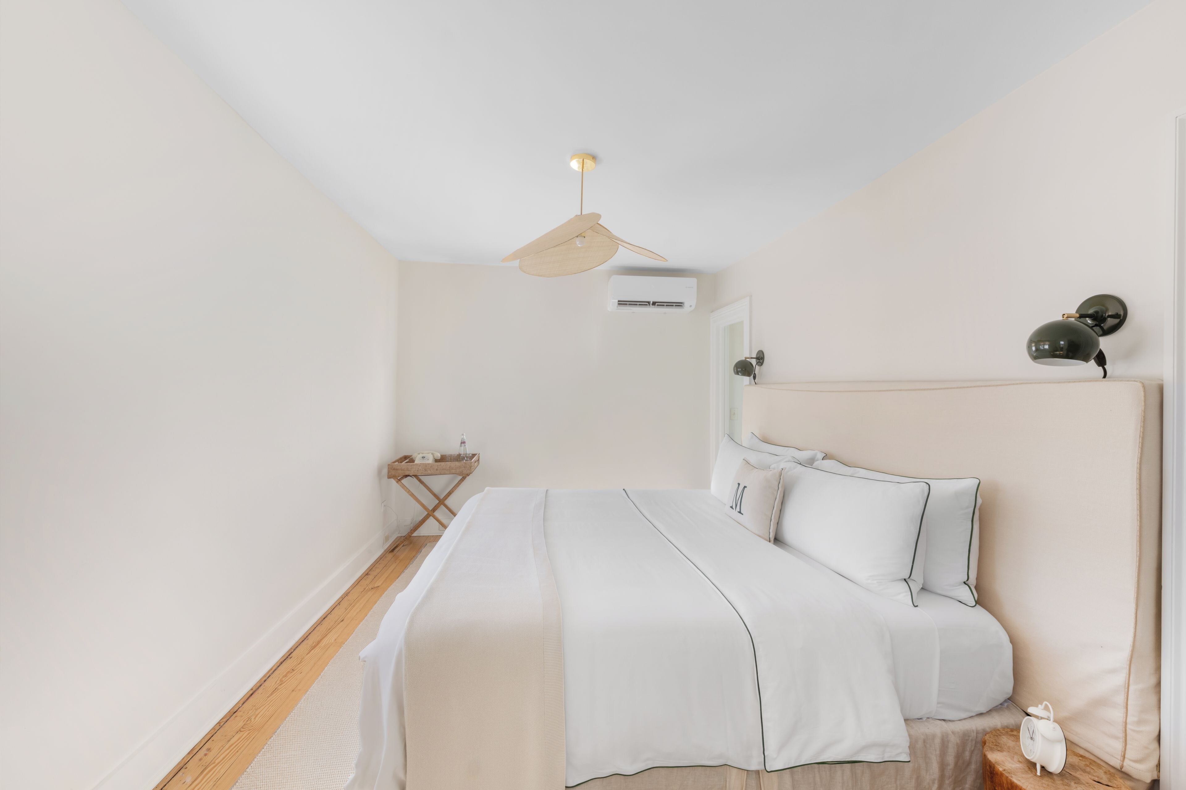 A minimalist bedroom with a bed, bedside table, and a ceiling fan.