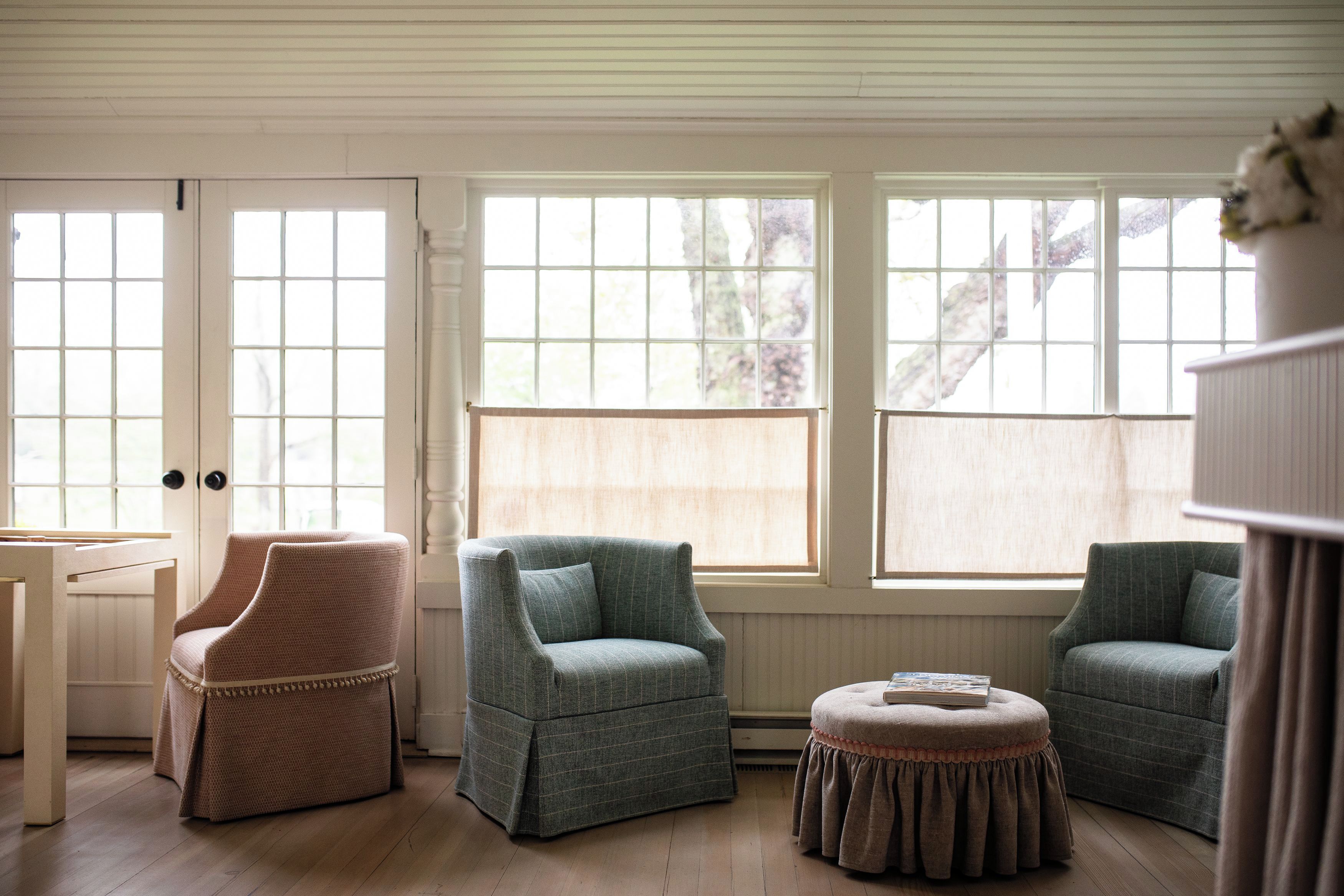 A room with two armchairs, a small table, and a window with a view of trees.