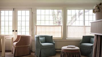 A room with two armchairs, a small table, and a window with a view of trees.