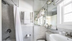 A modern bathroom with a bathtub, toilet, and sink. - The Maidstone (East Hampton)