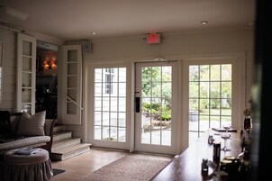 Habitación con una escalera que conduce a una puerta con panel de vidrio, una zona de bar con botellas y vistas al exterior.