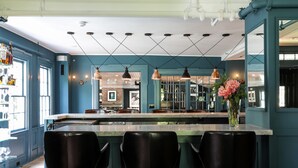 Une cuisine moderne dotée d’un îlot central, de tabourets de bar, de luminaires suspendus et offrant une vue sur l’espace repas.