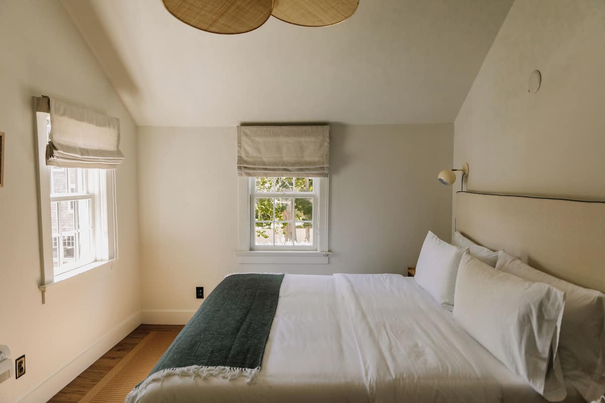 A bedroom with a large bed, a window with a view, and a ceiling fan.