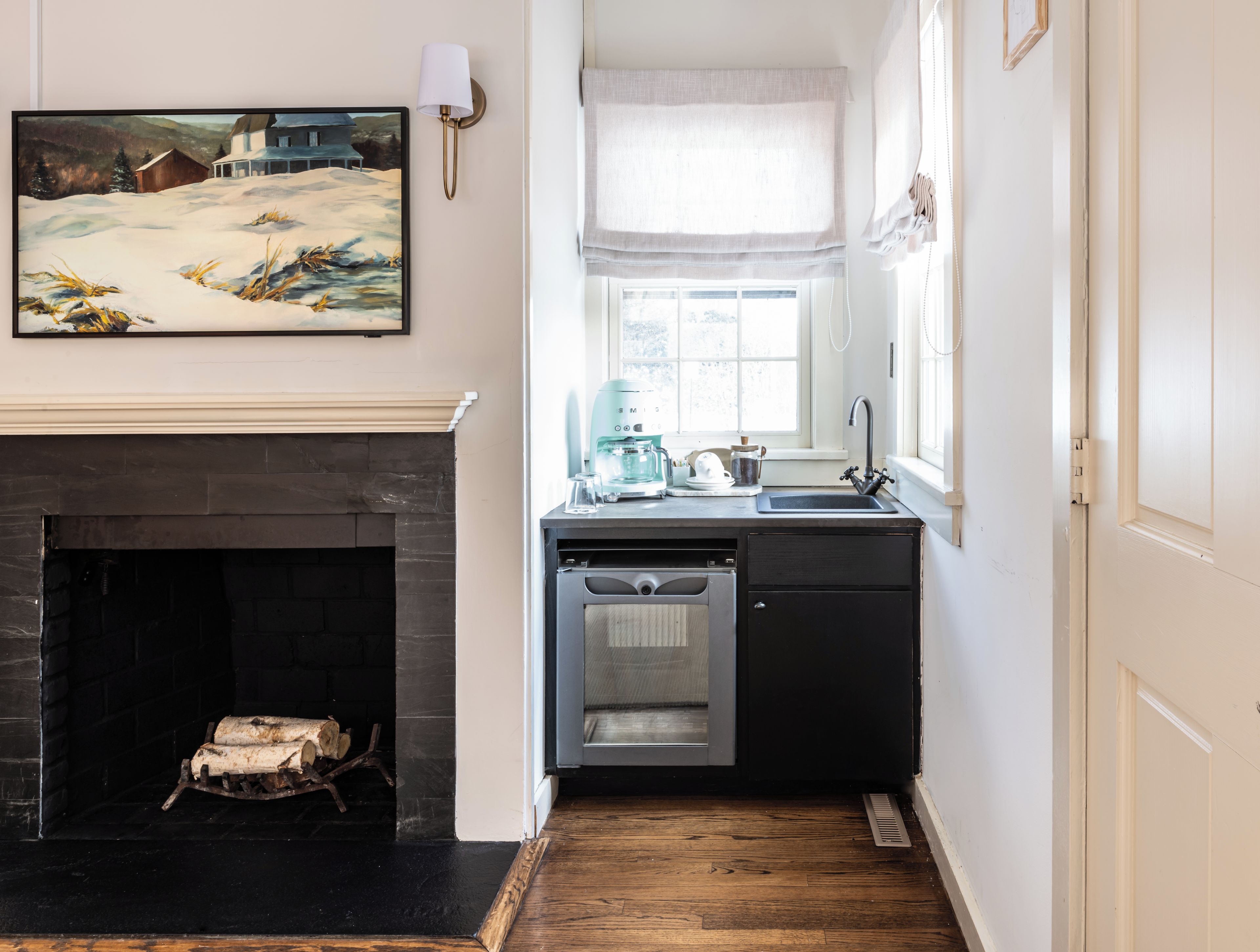 Una cocina con chimenea, un lavamanos y una ventana con vistas a una casa.