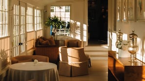 A hotel interior with a long corridor, seating areas, and a reception desk. - The Maidstone (East Hampton)