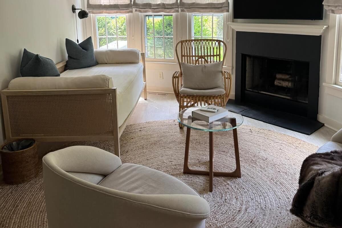 A living room with a sofa, armchair, and a television mounted above a fireplace.