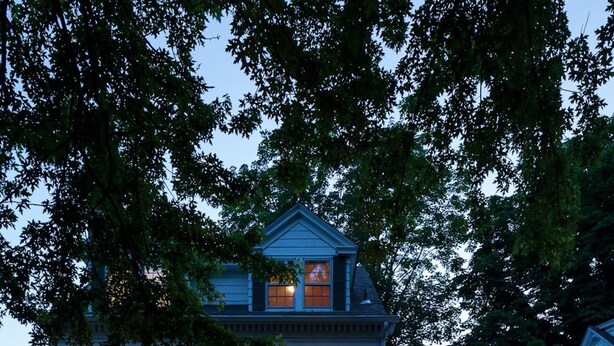 Une maison à deux étages avec un porche à l’avant, des colonnes et une entrée bien éclairée.