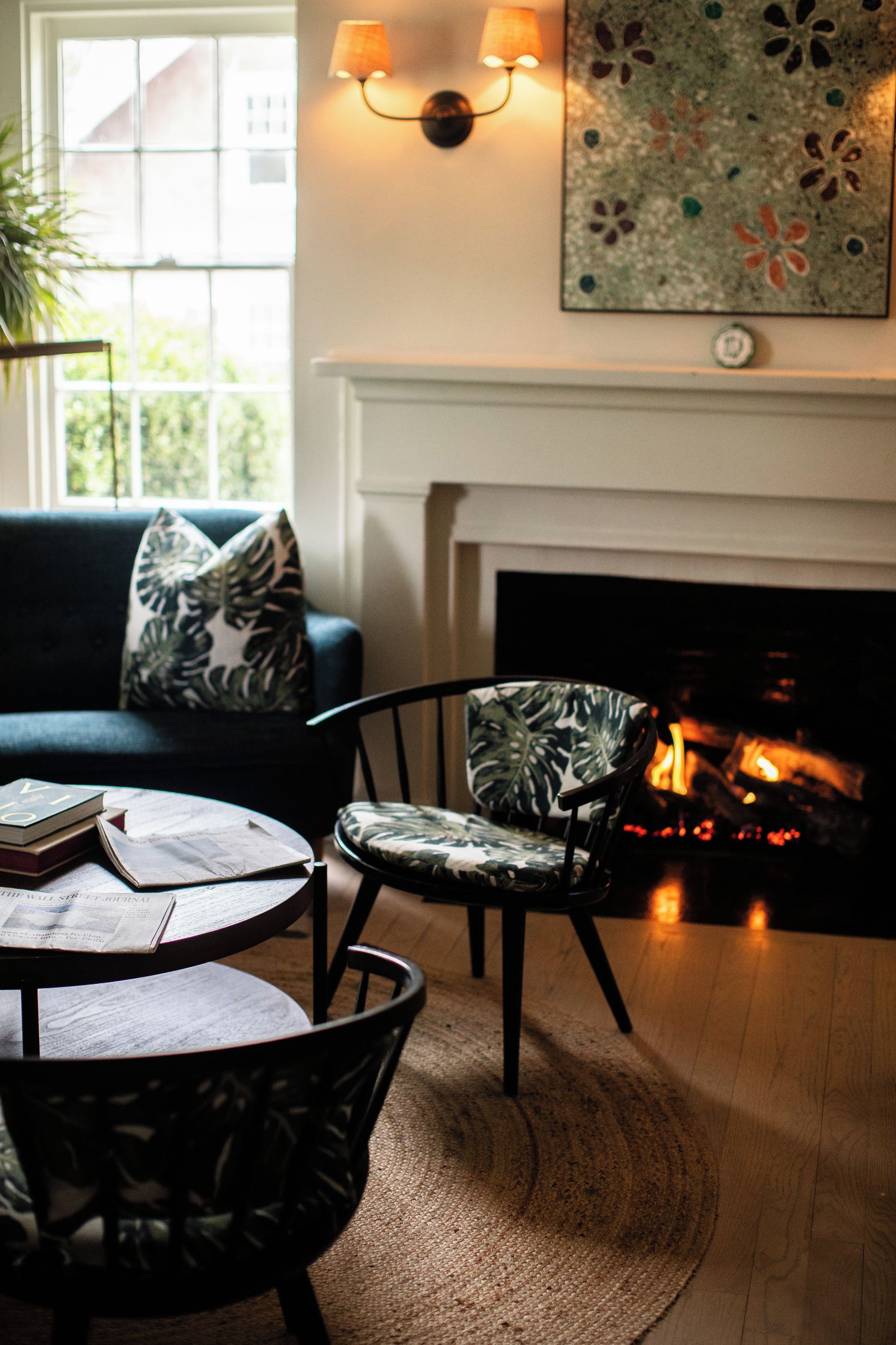 A cozy living room with a fireplace, a sofa, a chair, and a table with books.