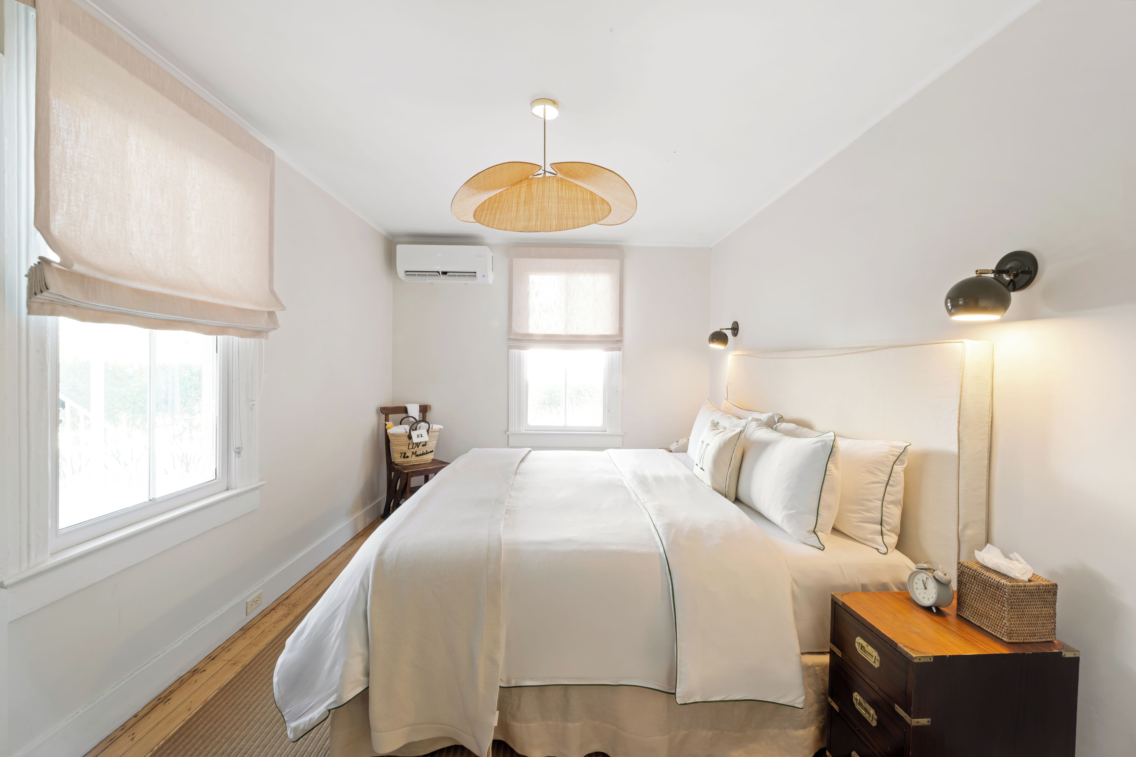 A bedroom with a bed, bedside table, lamp, and a window with blinds.